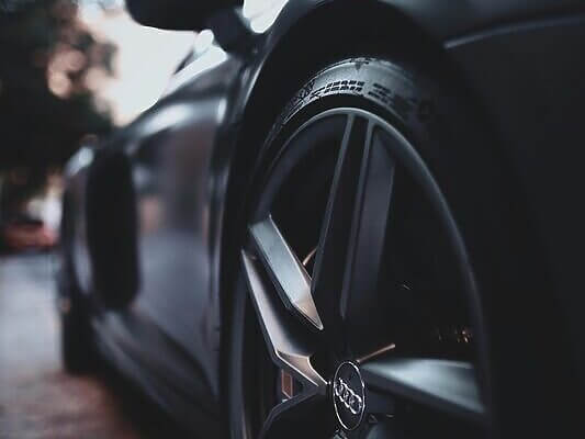 Close-up shot of a sleek, modern luxury sports car wheel with focus on design and details.