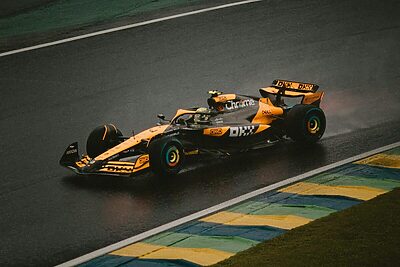 A Formula 1 car speeds around a wet track during an intense race, highlighting precision and speed.