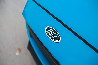 A detailed close-up of a blue Ford car emblem on a sunny day.