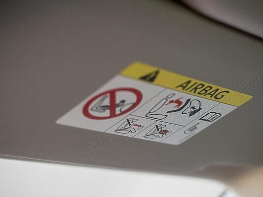 Detailed close-up of a car airbag warning sign on a vehicle interior panel.