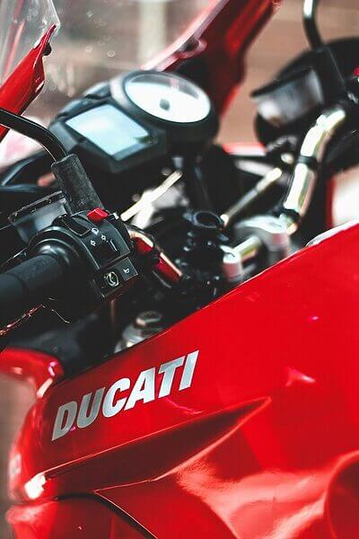 A detailed view of a red Ducati motorcycle dashboard and handlebars.