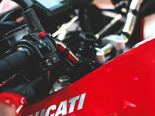 A detailed view of a red Ducati motorcycle dashboard and handlebars.