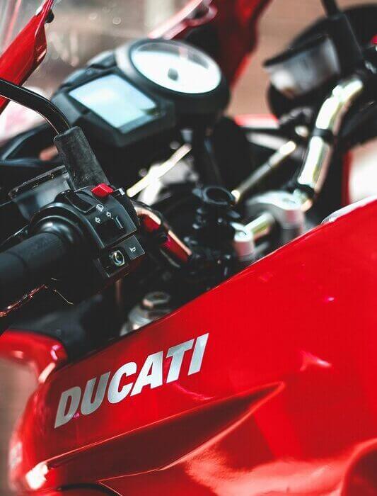 A detailed view of a red Ducati motorcycle dashboard and handlebars.