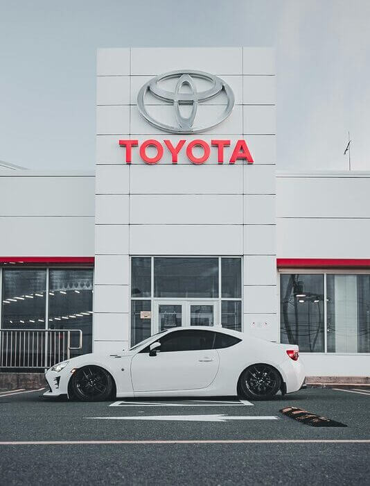 Sleek white car parked in front of a Toyota dealership showcasing modern automotive design.