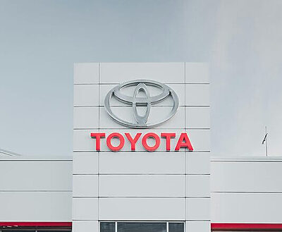 Sleek white car parked in front of a Toyota dealership showcasing modern automotive design.