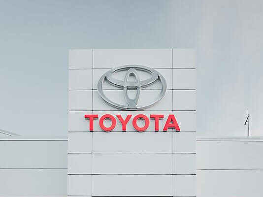 Sleek white car parked in front of a Toyota dealership showcasing modern automotive design.