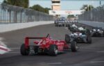 Des spectateurs suivent des monoplaces de Formule 1 depuis une tribune au bord d’un circuit.
