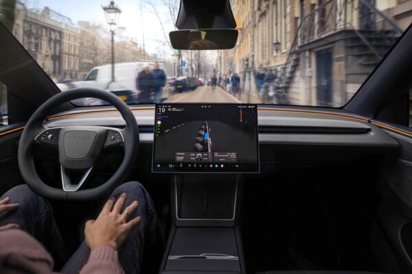 Une Tesla circulant sur route avec le système de conduite FSD actif à bord.
