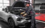 Un automobiliste examine une voiture immobilisée au bord de la route.