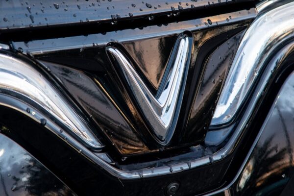 Un véhicule électrique de la marque VinFast présenté devant un bâtiment industriel.