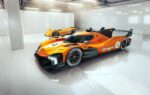 Le prototype McLaren MCL-HY en livrée orange sur un circuit.
