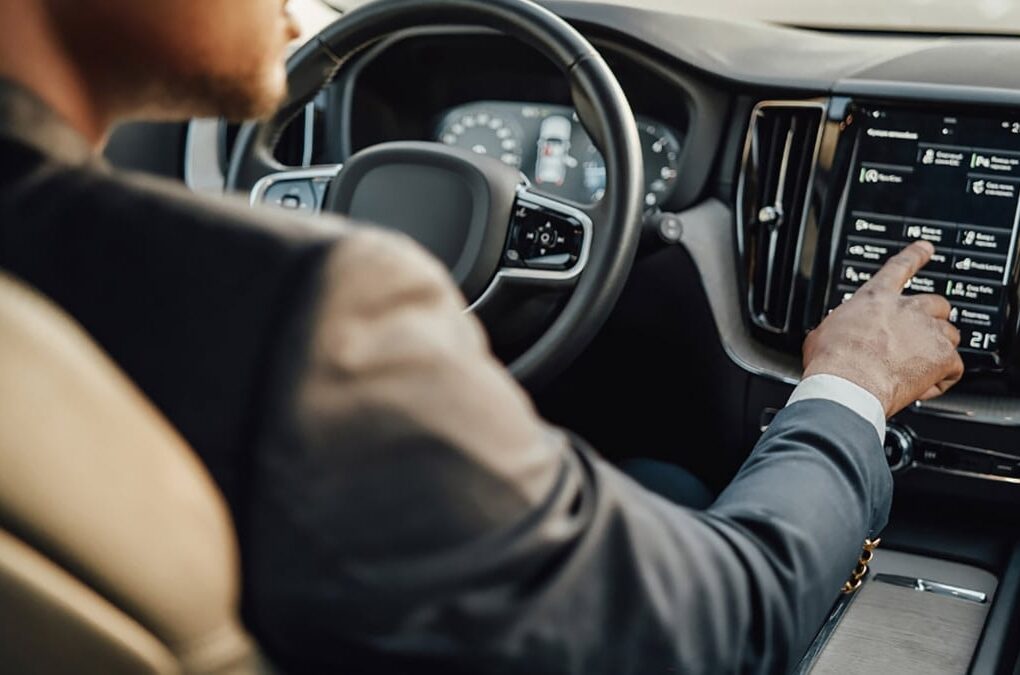 Un conducteur utilise l’écran tactile central d’une voiture tout en roulant.