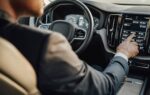 Un conducteur utilise l’écran tactile central d’une voiture tout en roulant.