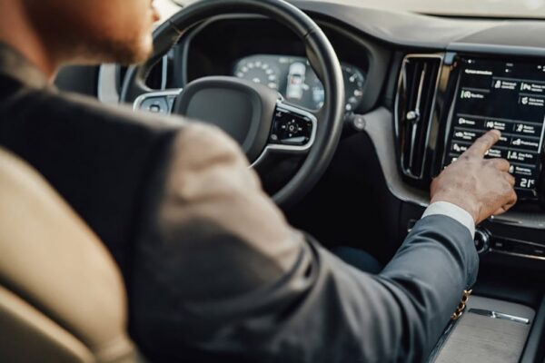 Un conducteur utilise l’écran tactile central d’une voiture tout en roulant.