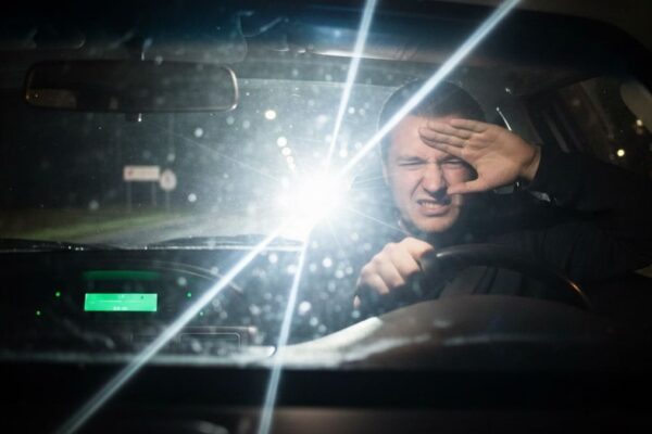 Des phares de voiture éclairent une route de nuit face à un automobiliste.